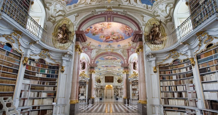 Biblioteca dell’abbazia di Admont con scaffali bianchi e dorati, affreschi sulle volte e luce dalle finestre